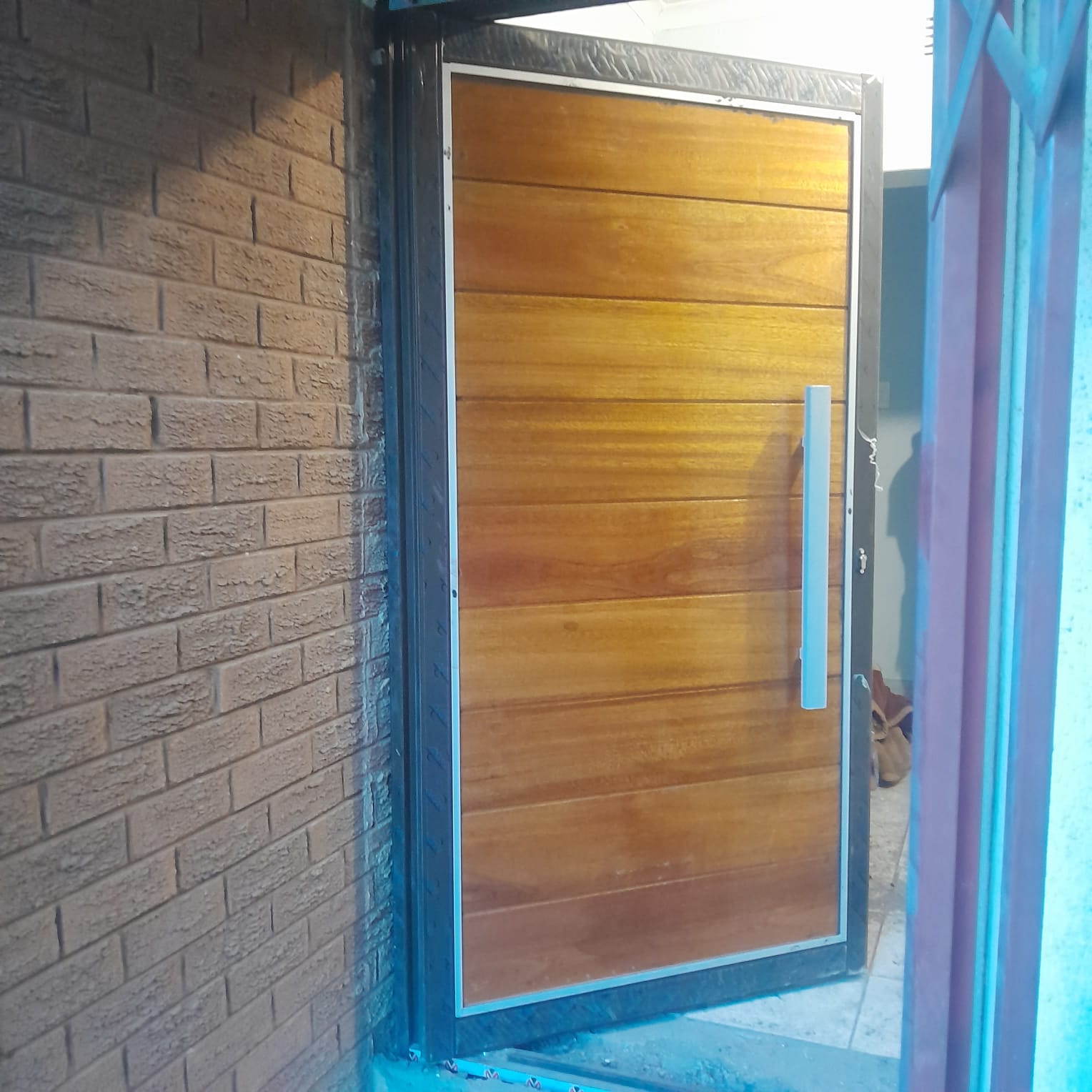 Warm timber horizontal-slat pivot door set in a slim aluminium frame